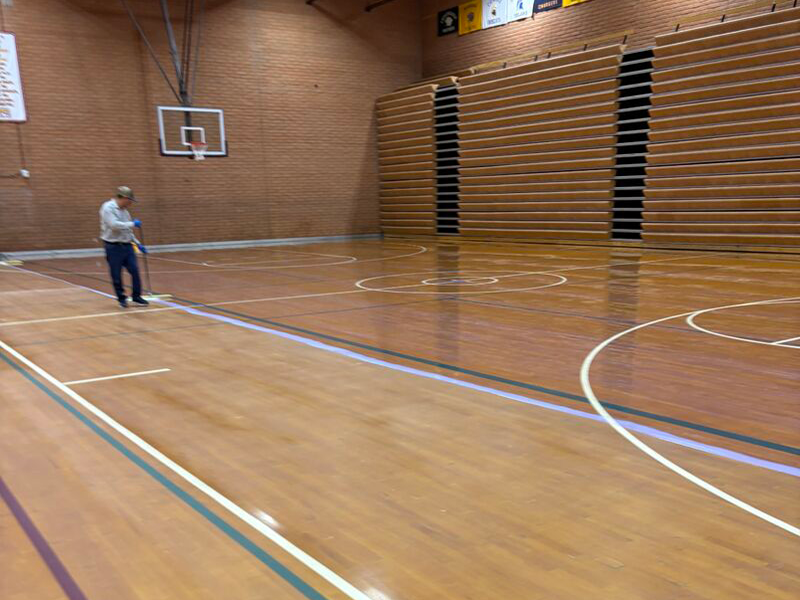 worker restoring gymnasium floor